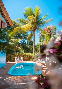 una piscina con una palmera en un patio en Pousada Bambu, en Itacaré
