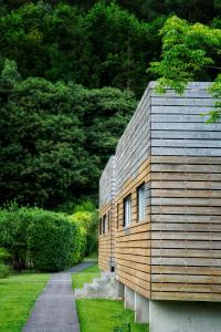 a house with a wooden wall and a path at Furnas Lake Forest Living in Furnas