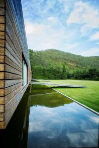 a building with a pool of water next to a field at Furnas Lake Forest Living in Furnas