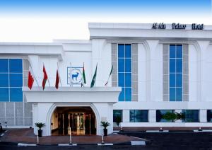 un bâtiment avec drapeaux devant lui dans l'établissement Al Ain Palace Hotel Abu Dhabi, à Abu Dhabi