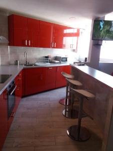 eine Küche mit roten Schränken und 2 Barhockern in der Unterkunft Apartamento en Castellón RENFE in Castellón de la Plana