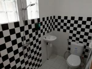 La salle de bains est pourvue d'un mur en damier noir et blanc. dans l'établissement Lia Homestay, à Yogyakarta