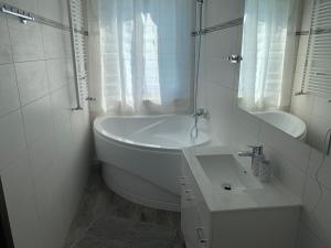 a white bathroom with a tub and a sink at Botel Gracia in Bratislava