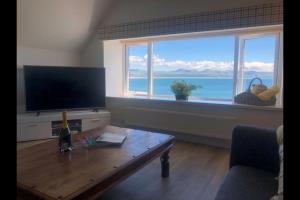 a living room with a television and a table and a window at The Iris in Criccieth