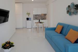 un soggiorno con divano blu e una cucina di La Casa Di Dodo a Taormina