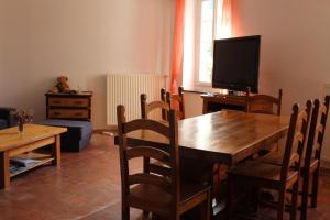 a dining room with a wooden table and a television at Au Coeur de Rennes Gîte in Rennes-les-Bains