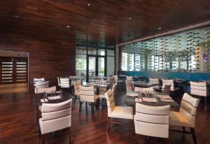 a dining room with tables and white chairs at Zota Beach Resort in Longboat Key
