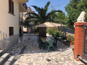 een patio met een tafel en stoelen en een parasol bij Villa Rosa Roccamonfina in Roccamonfina