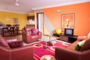 sala de estar con sillas de cuero y TV en Calabash Residence Apartments, en Kotu