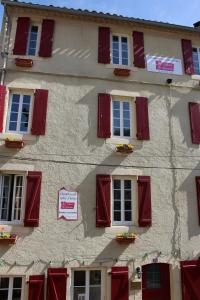 un bâtiment avec des volets rouges et un panneau sur celui-ci dans l'établissement Au Coeur de Rennes Gîte, à Rennes-les-Bains