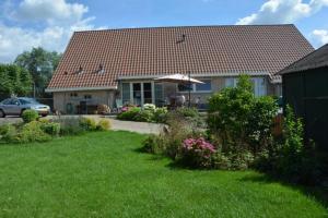 a house with a roof with a yard with flowers at B&B de Oude Hofstee in Maasdam