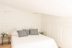 un letto bianco con due cuscini grigi sopra di Apartamentos Principe 7 a Madrid