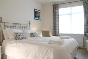 a bedroom with a large white bed with towels on it at The Iris in Criccieth
