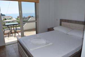 a bedroom with a bed and a balcony with a table at Velco BB Himara in Himare