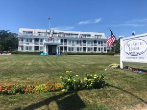 duży biały budynek z znakiem i kwiatami w obiekcie The Atlantic House w mieście Narragansett