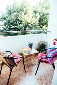 2 Stühle und ein Tisch auf einem Balkon mit Fenster in der Unterkunft Sophies World in Sarajevo
