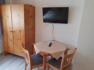 einen kleinen Tisch mit Stühlen und einen TV an der Wand in der Unterkunft Gasthof Pension Weißes Rössl in Floß