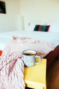 eine Tasse Kaffee auf einem Buch neben einem Bett in der Unterkunft Sophies World in Sarajevo