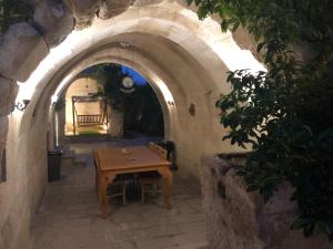 łuk z drewnianym stołem w kamiennym budynku w obiekcie Kayhan Cave Villa w mieście Ürgüp