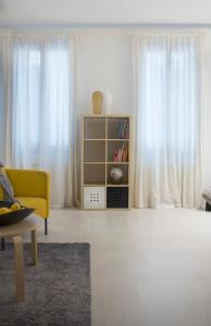 ein Wohnzimmer mit einem gelben Sofa und weißen Vorhängen in der Unterkunft Uma Apartments in Venedig