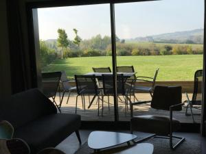 a patio with a table and chairs and a large window at Coolcottage des 2 Caps in Leulinghen-Bernes +9 photos