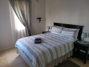 a bedroom with a bed with a striped blanket and a window at Serengeti Self Catering Units in Bellville