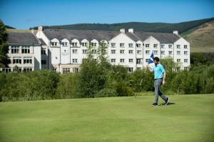 un hombre está jugando golf en un green con un club en Macdonald Cardrona Hotel, Golf & Spa, en Peebles