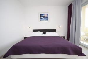 Pension Villa Rosa في ريتنا: غرفة نوم بسرير وبطانية ارجوانية