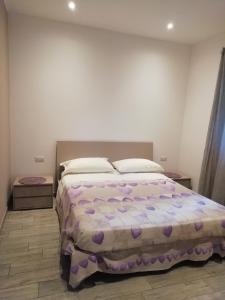 een slaapkamer met een groot bed met een paars dekbed bij La casa di Beppe c cir D1135 in Lanzo dʼIntelvi