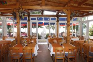 a restaurant with wooden tables and chairs and windows at Pension Villa Rosa in Rtina