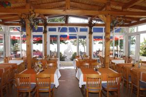 um restaurante com mesas e cadeiras de madeira e janelas em Pension Villa Rosa em Rtina