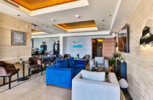 a lobby with blue couches and chairs and a bar at Hotel California by Aycon in Sveti Stefan