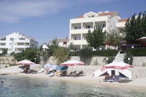a group of people sitting on a beach with umbrellas at Pension Villa Rosa in Rtina +20 photos
