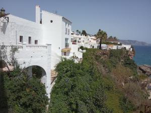 a white building on a hill next to the ocean at Casa Eva - Adults Only in Nerja