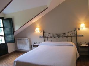 a bedroom with a bed with white sheets and two lights at Apartamentos Rurales Casa Baltasar in Monasterio De Hermo
