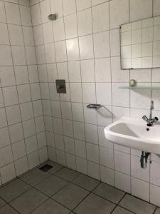a white tiled bathroom with a sink and a mirror at Trekkershut/kampeerhut in Hulst