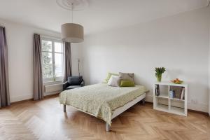 a white bedroom with a bed and a chair at Am Pavillon, Bed&Kitchen in Bern