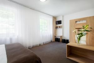 a hotel room with a bed and a vase of flowers at Hotel Bon in Tanvald