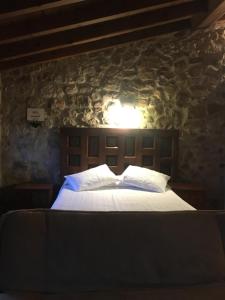 - une chambre avec un lit et un mur en pierre dans l'établissement Hostal Rural Las Nubes, à Salas de los Infantes
