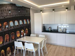 a kitchen with a white table and white chairs at Klimatyzowany Apartament ROMA z garażem podziemnym in Kielce
