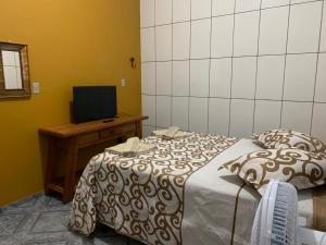 Schlafzimmer mit einem Bett und einem Schreibtisch mit einem TV in der Unterkunft casa temporada tiradentes in Tiradentes