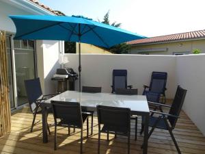 a table and chairs with a blue umbrella on a patio at Villa du Cabestan in Andernos-les-Bains