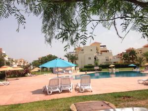 um grupo de cadeiras e um guarda-sol junto a uma piscina em TRIPLEX LA MARINA SAIDIA em Saidia 