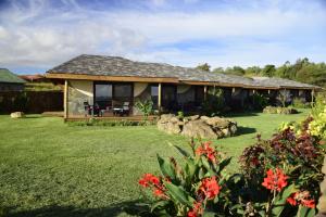 uma casa com um quintal com flores vermelhas em Takarua Lodge em Hanga Roa