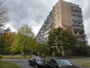 dos autos estacionados frente a un edificio alto en Purvciems, Ieriķu apartment, en Riga