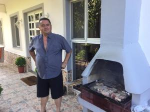 a man standing next to an outdoor oven at Villa Dede Nikolla in Durrës