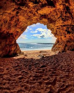 a cave on the beach with the ocean in the background at Alameda Hostel in Portimão