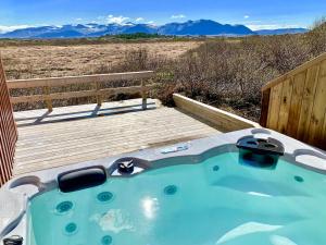 a hot tub on a wooden deck with mountains in the background at Klettur in Borgarnes