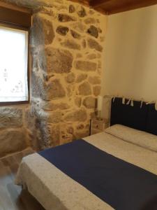 una camera da letto con una parete in pietra, un letto e una finestra di Casa en armenteira entera ideal para peregrinos precio segun numero de huéspedes , y grupos, a Pontevedra