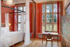 a bedroom with a bed and a desk and windows at Chateau Herálec Boutique Hotel & Spa by L'Occitane in Herálec